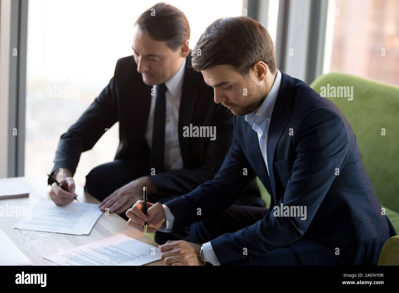 Successful businessmen in suits signing contract, partnership agreement Stock Photo