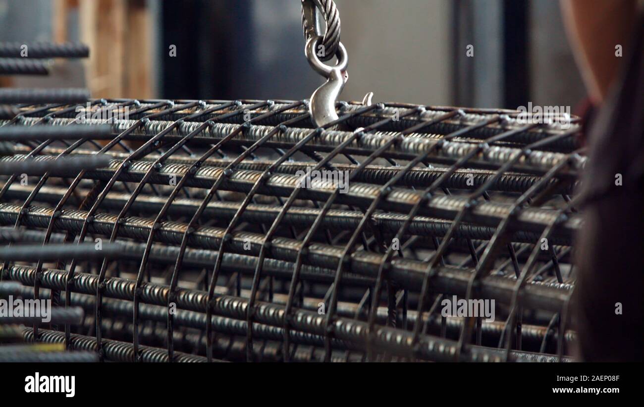Aluminum circular column reinforcement stacked with big wire rope sling onto crane block in preparation of heavy lifting in metalworking factory. Heav Stock Photo