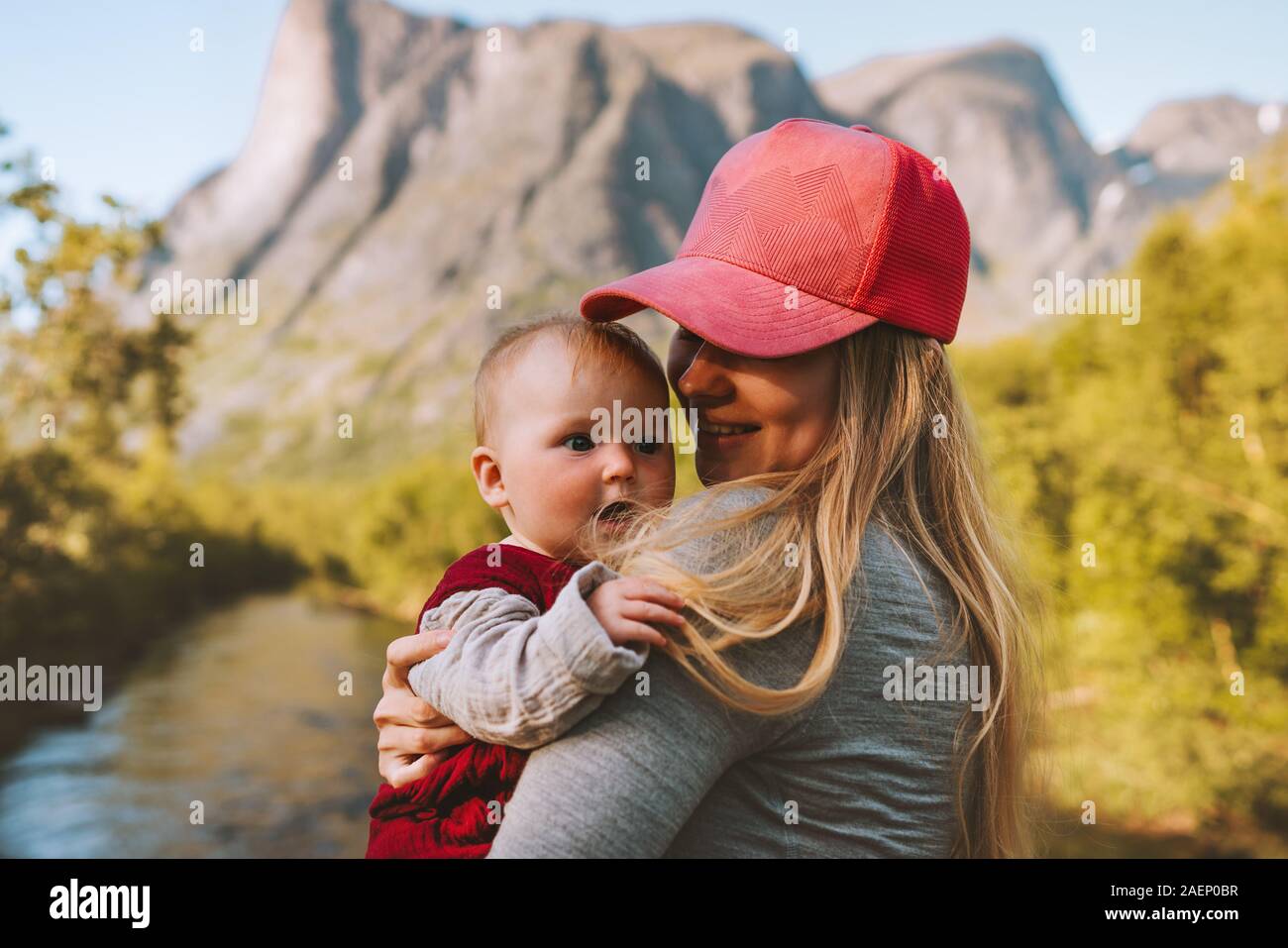 Mother and infant baby walking outdoors family travel healthy lifestyle young woman holding child summer vacations in mountains Mothers day holiday Stock Photo