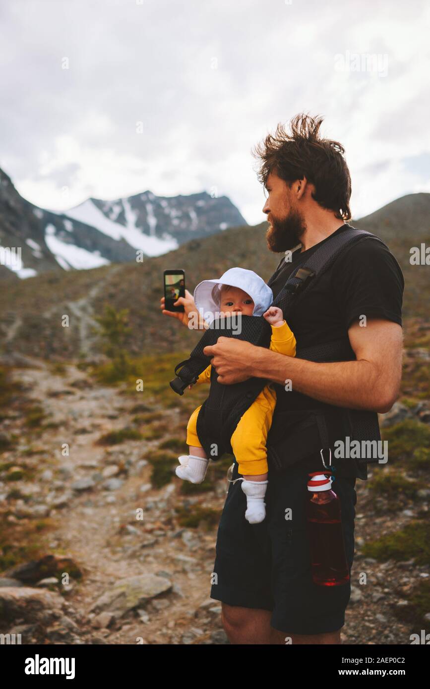Father with baby taking selfie by smartphone travel in mountains family adventure vacations hiking with kids healthy lifestyle outdoor blogger influen Stock Photo