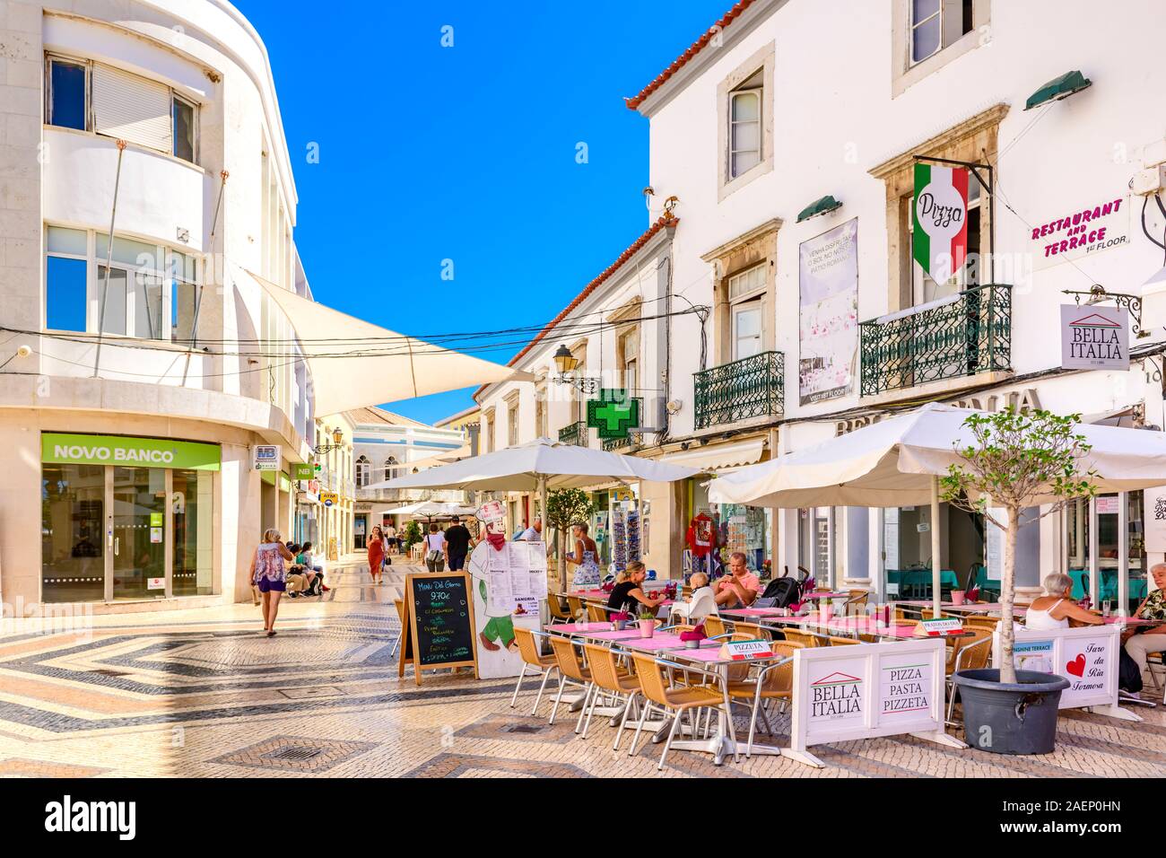 Outdoor restaurant in street paved with traditional Portuguese cobbles cobble stones, calcada, the shopping centre Faro, East Algarve Portugal. Stock Photo