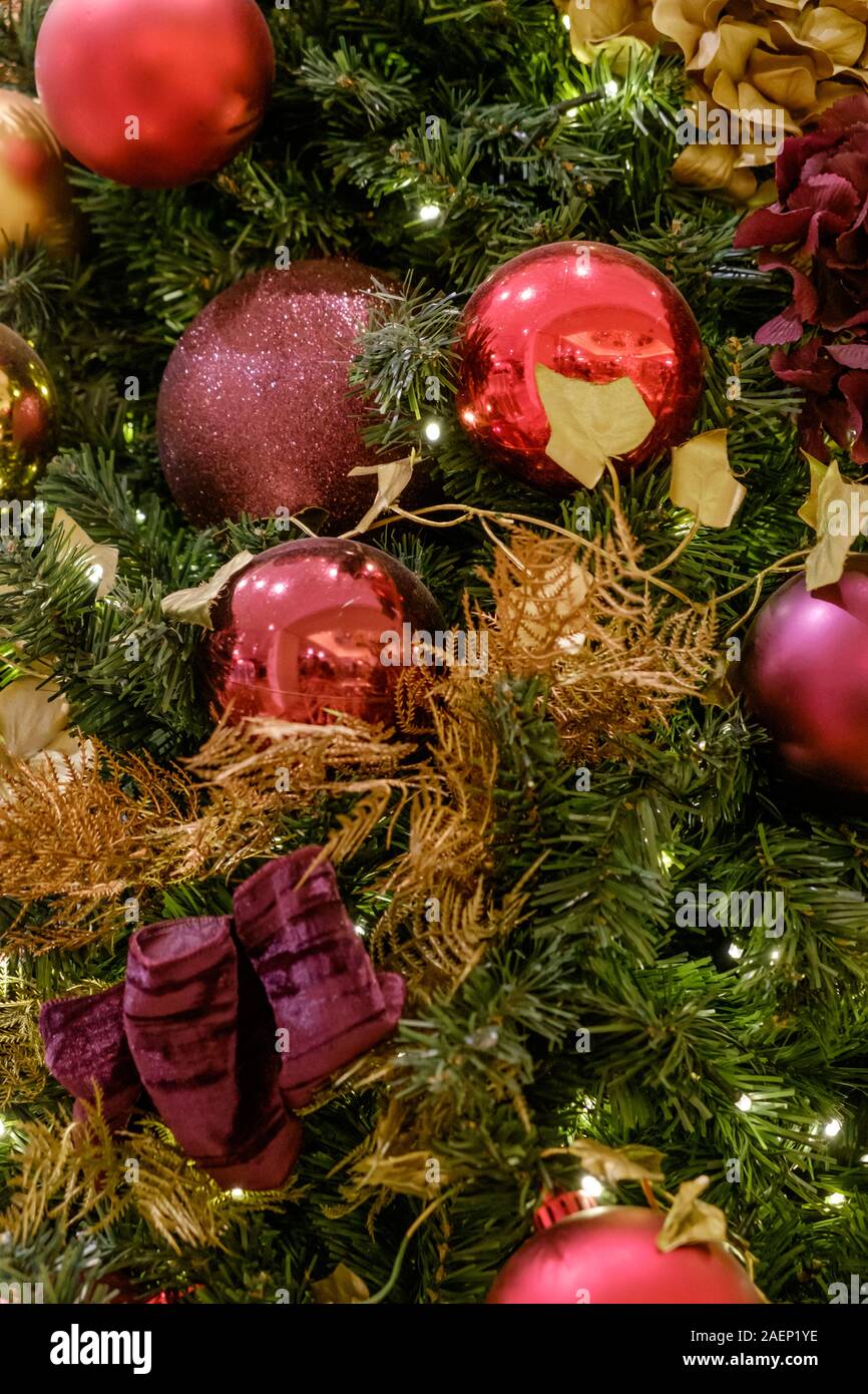 Close Up of Christmas Tree with colourful red purple and gold baubles and decorations. Stock Photo