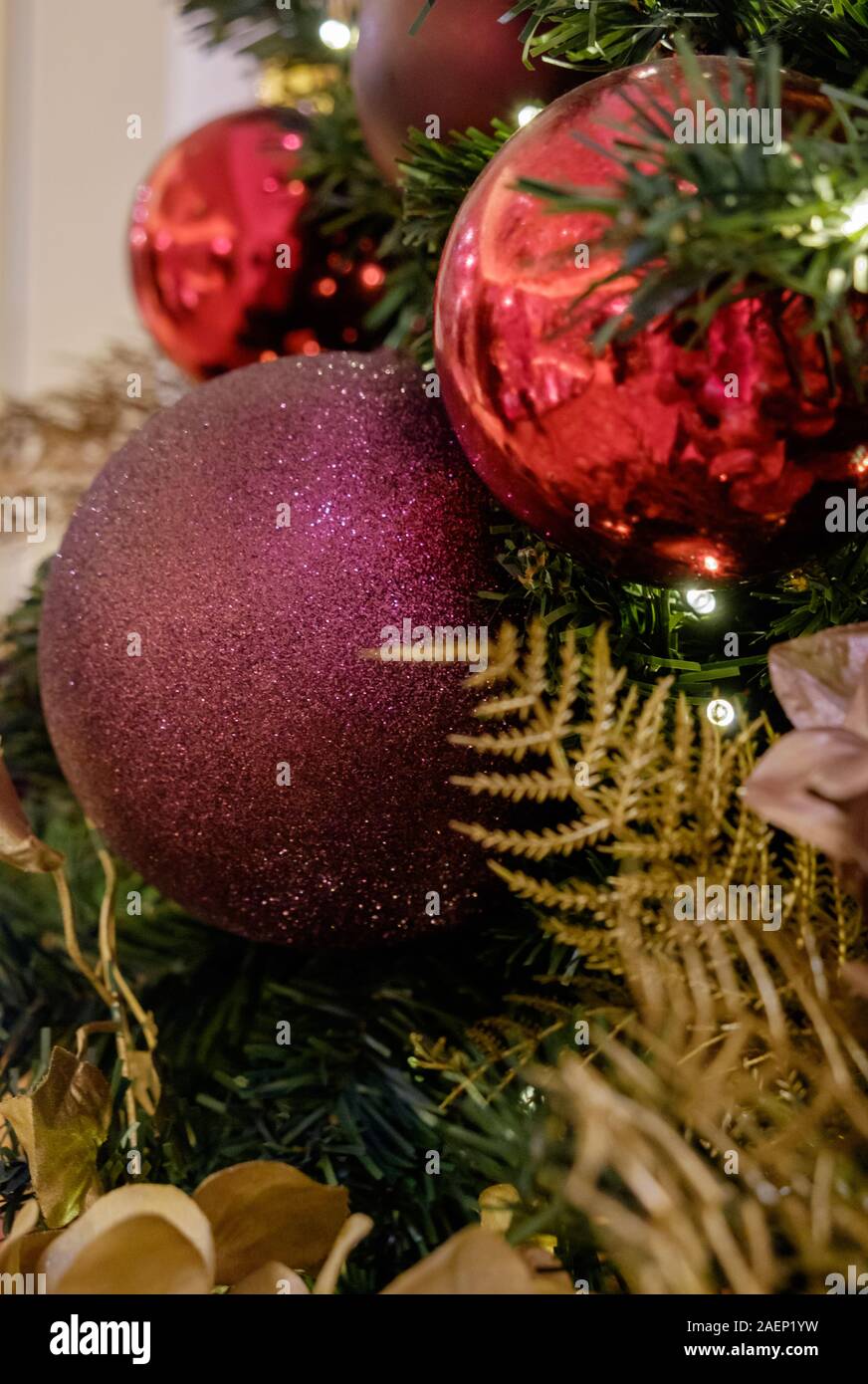 Close Up of Christmas Tree with colourful red purple and gold baubles and decorations. Stock Photo