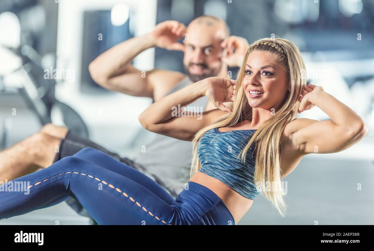 Woman and man athletic couple strengthen abdominal muscles in gym. Core strength training exercise. Stock Photo