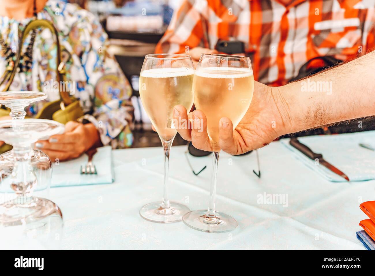 The waiter serves two glasses of white wine for a couple.  Man and woman have a lunch on a restaurant in Italy Stock Photo