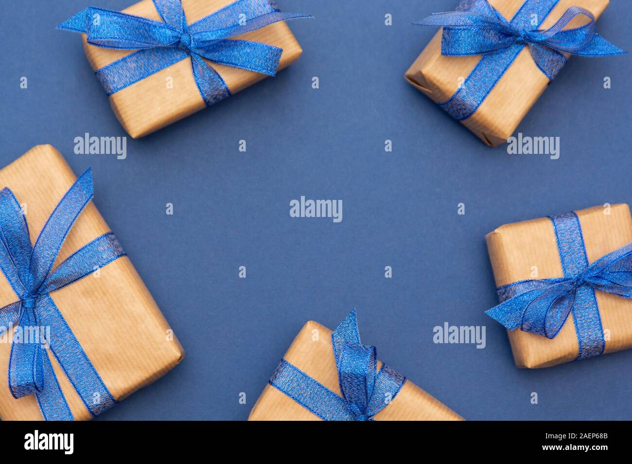 Christmas or birthday presents frame or border. Craft paper wrapped gift boxes on blue background, flat lay. Copy space. Stock Photo