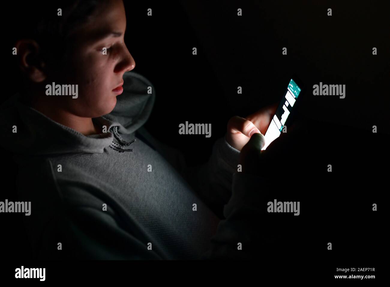 Teenager using a smartphone, sending a message. Teenager using his two thumbs to write a message on the keyboard of his smartphone Stock Photo