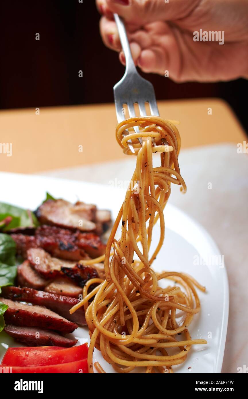 Sliced BBQ pork belly with pasta and salad Stock Photo