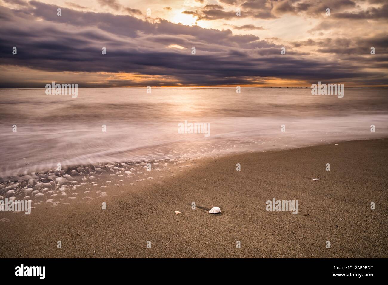 sunset reflected on the waves of the sea in winter on December in Lido di Ostia Rome Italy Stock Photo