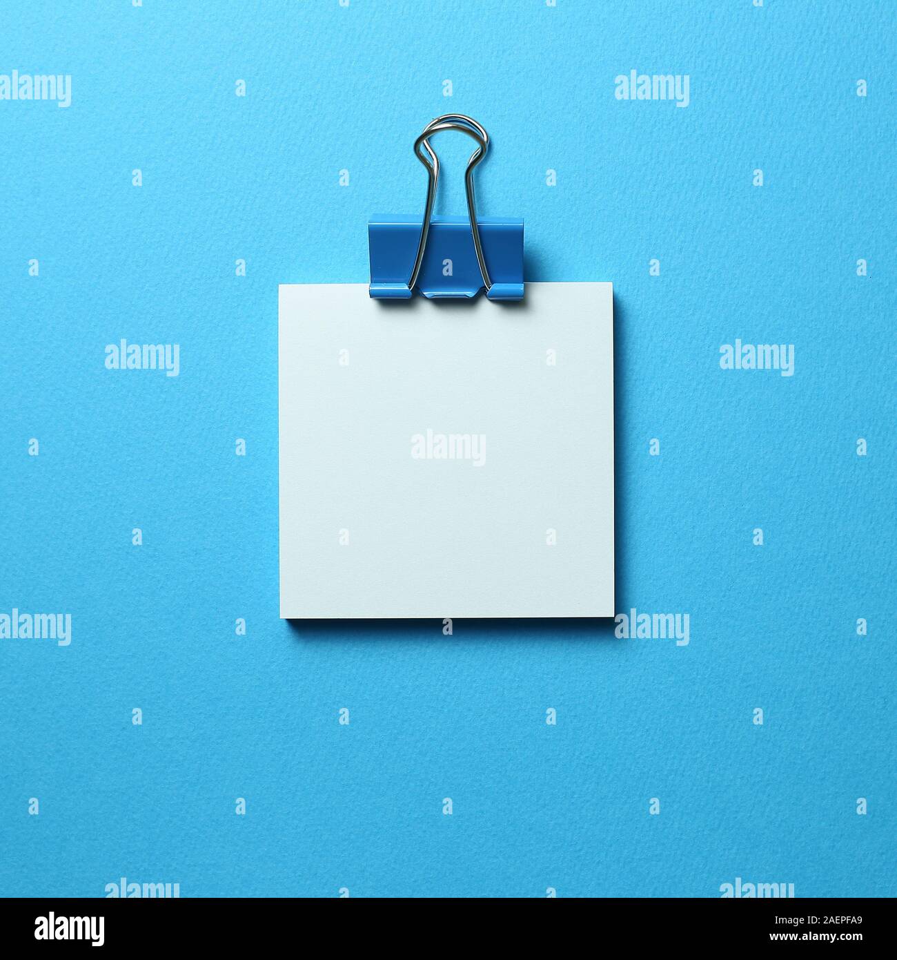 Blue memo pad sticky note and clip on blue background Stock Photo