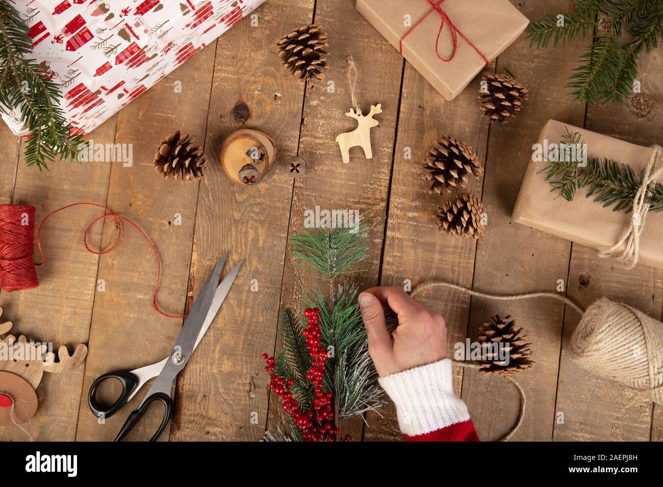 Man hand placing a Christmas bite on vintage wooden work table. Christmas concept. Top view Stock Photo