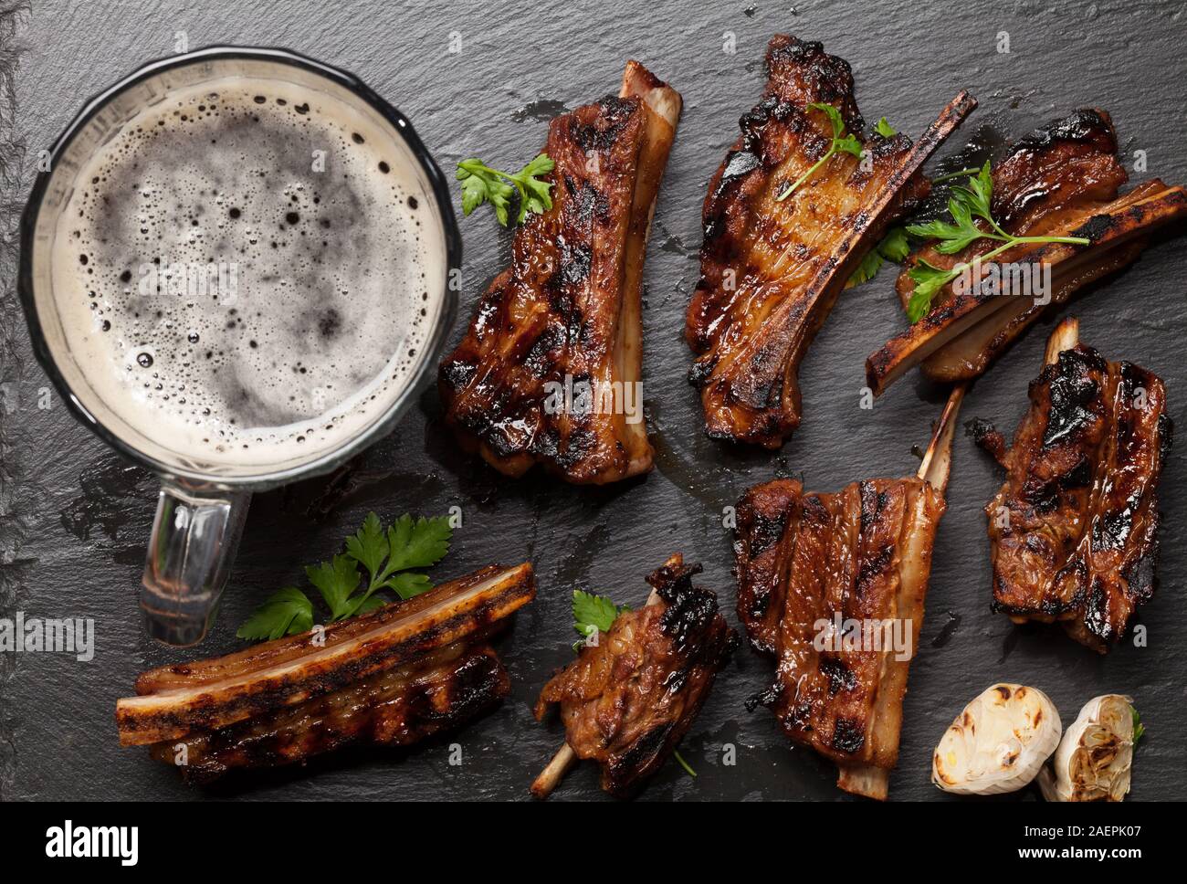 Barbecue beef ribs with bbq sauce sliced on a stone board with beer mug. Top view flat lay Stock
