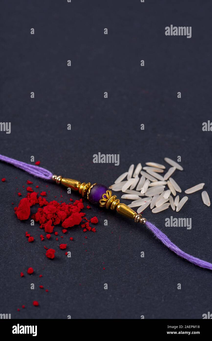 Raksha Bandhan : Rakhi with rice grains and kumkum on black background ...