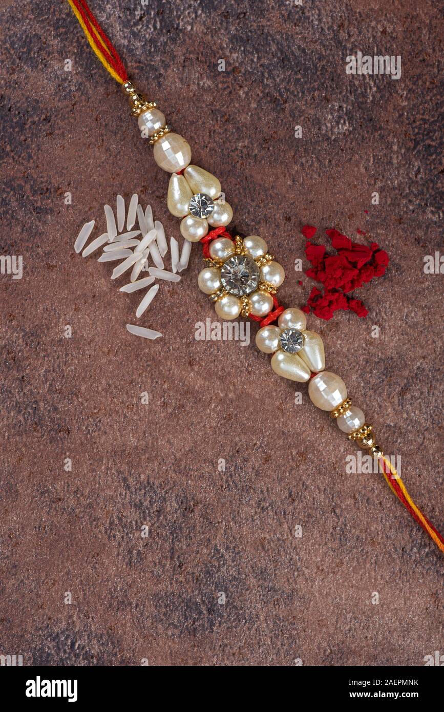 Raksha Bandhan : Rakhi with rice grains and kumkum on stone background ...