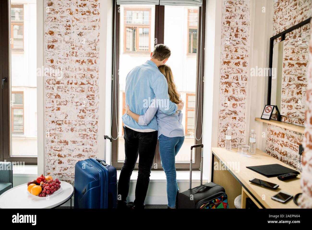 Back view of happy loving couple in hotel room, hugging and standing on ...