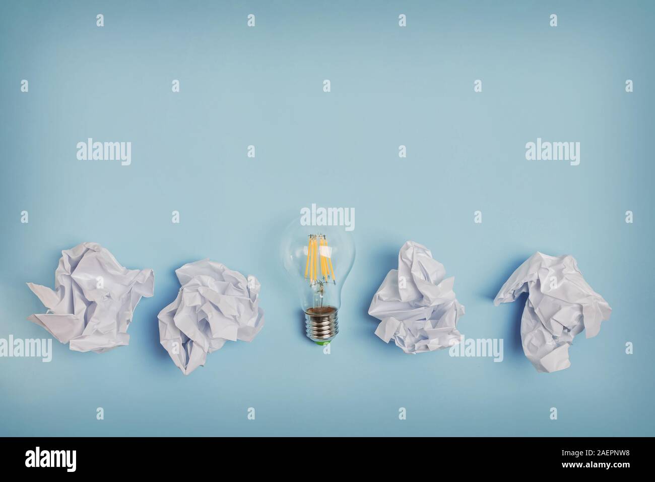 Crumpled papers and lightbulb on the blue background. Stock Photo
