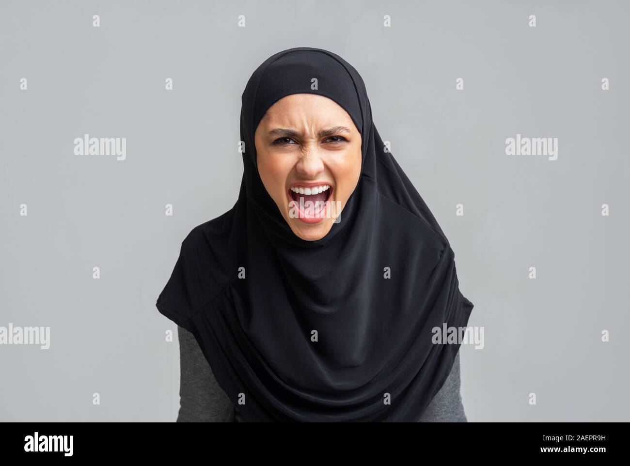 Angry muslim girl in hijab screaming loud, emotionally protesting about something Stock Photo