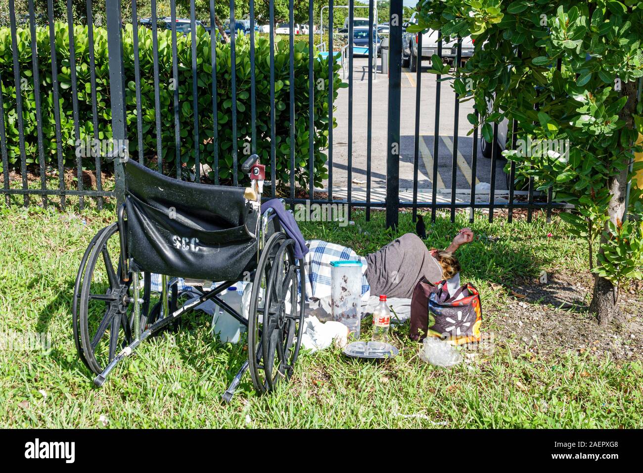 Miami Florida,Hialeah,parking lot,man,homeless,disabled,wheelchair,sleeping on grass,empty plastic food containers,FL191025013 Stock Photo