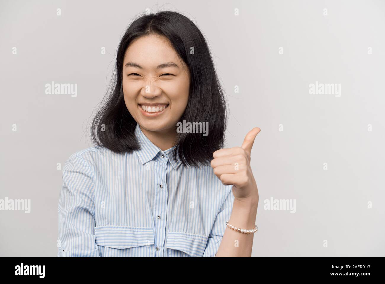 Girl with snow white teeth laughs shows thumbs up Stock Photo - Alamy