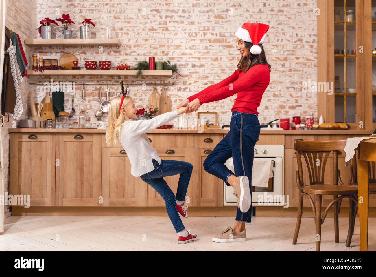 Smiling female holding her daughters hands in the kitchen Stock Photo ...