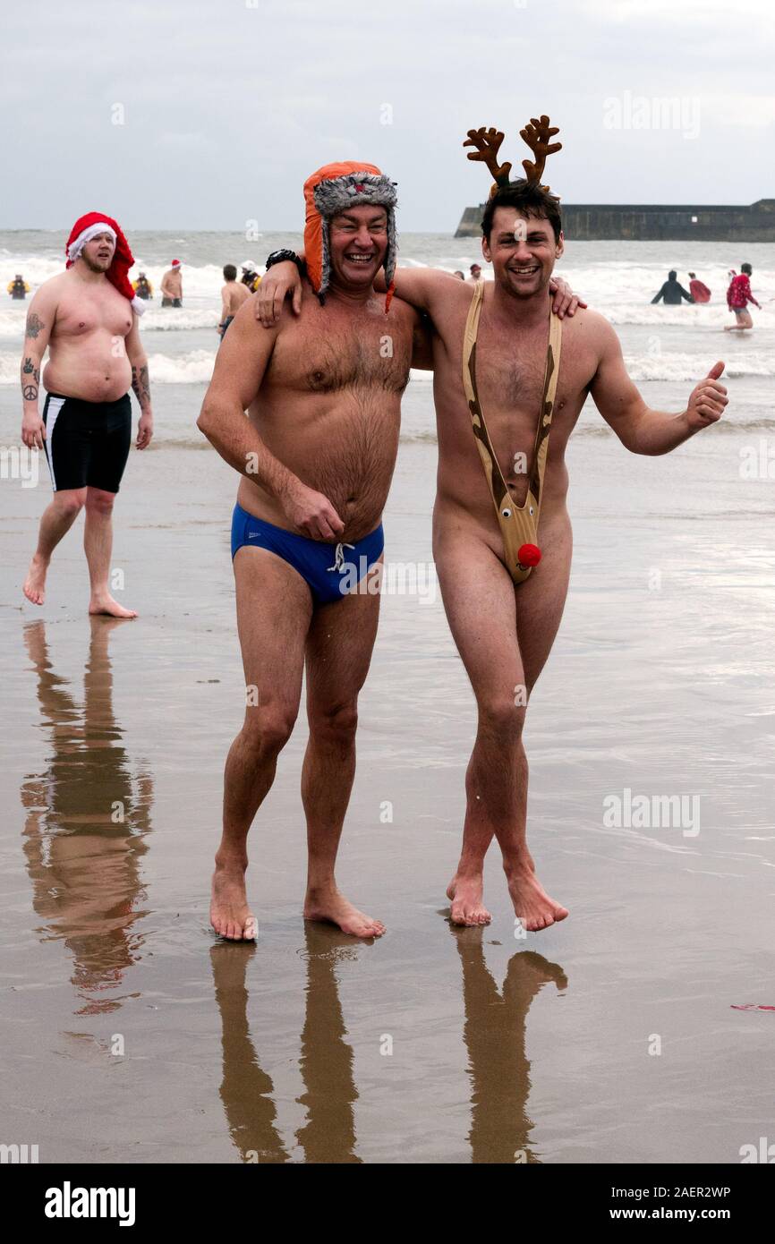 Christmas Day fancy dress swim in the cold sea at Porthcawl, a seaside town in South Wales, with men in thong and swimming trunks. Stock Photo