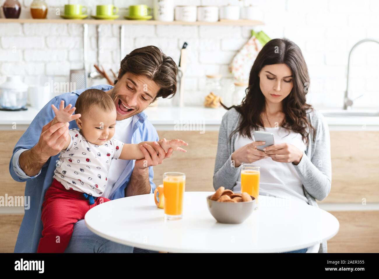 Absorbed woman browsing on phone, ignoring her family Stock Photo