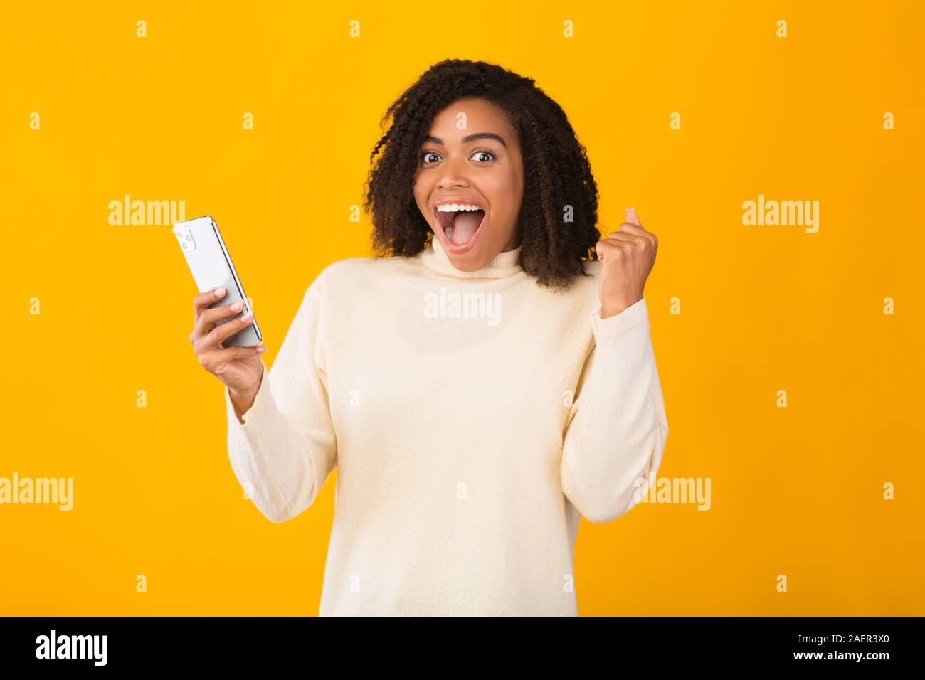 Excited african girl holding iPhone 11 pro max Stock Photo