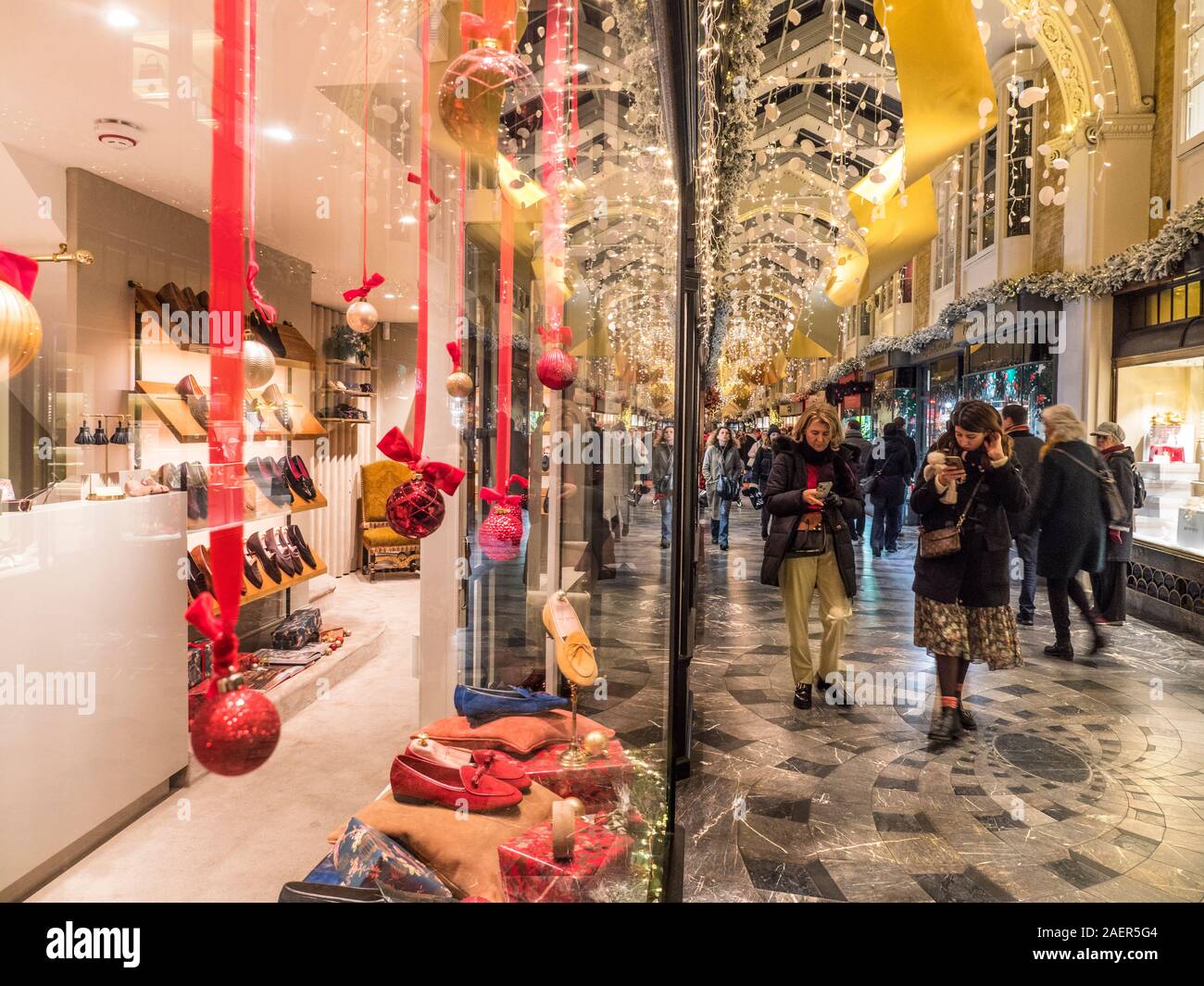 BURLINGTON  ARCADE CHRISTMAS 2019  FESTIVE WINDOW DISPLAY  SHOPPING SHOPPERS SMARTPHONES WOMEN INTERIOR charming olde worlde Burlington Arcade in its 200th year in Piccadilly with traditional Christmas decorations and shoppers London UK Stock Photo