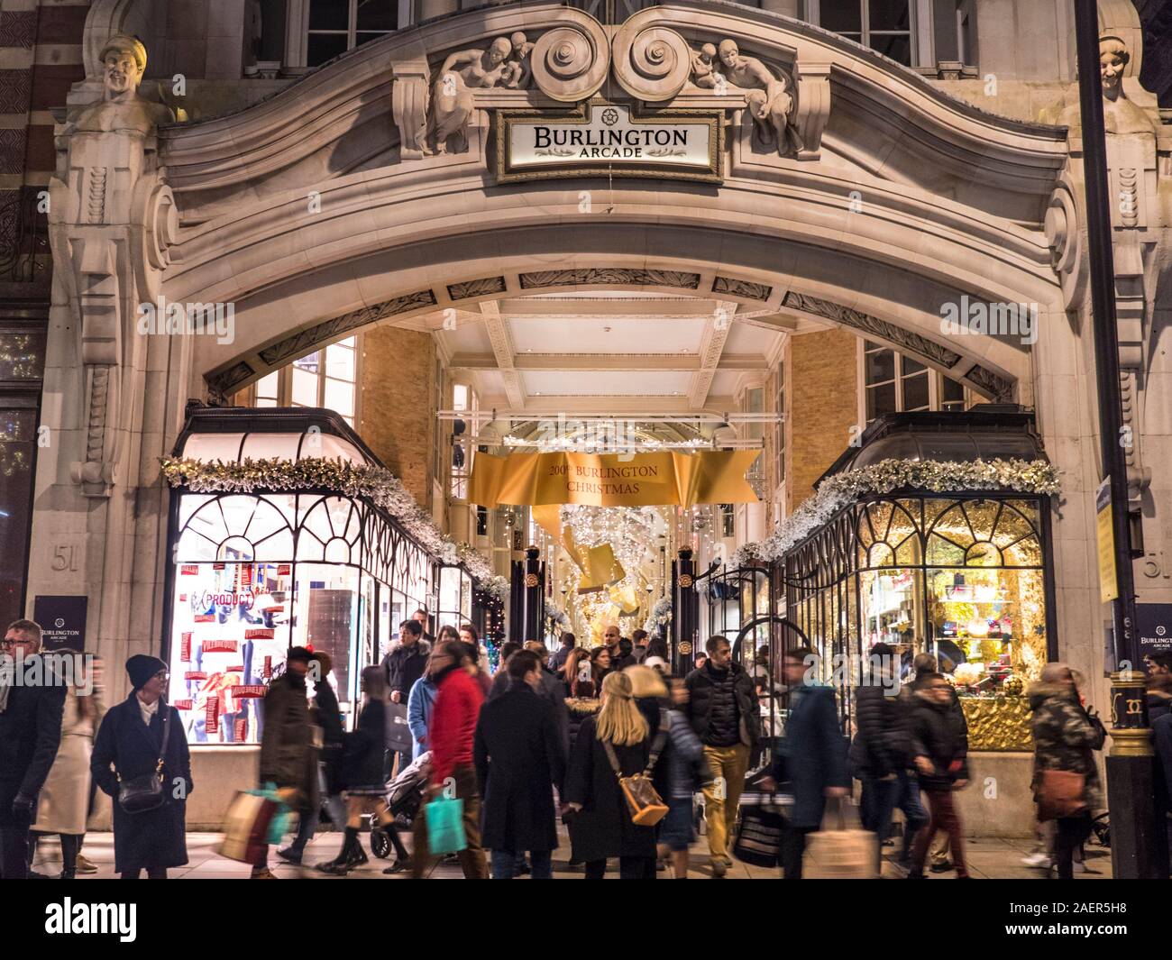 Burlington Arcade Piccadilly busy shoppers shopping at Christmas traditional luxury London shopping arcade busy entrance with shoppers shopping crowds in Piccadilly with Christmas lights and decorations at dusk Piccadilly London UK Stock Photo