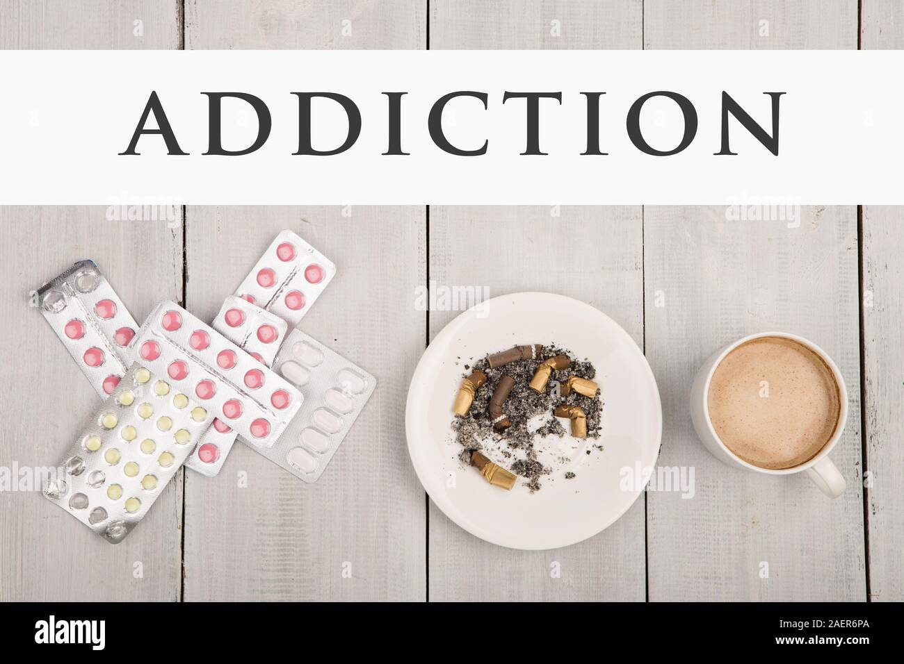 Cup of coffee, cigarettes and pills and text Addiction on white wooden table Stock Photo
