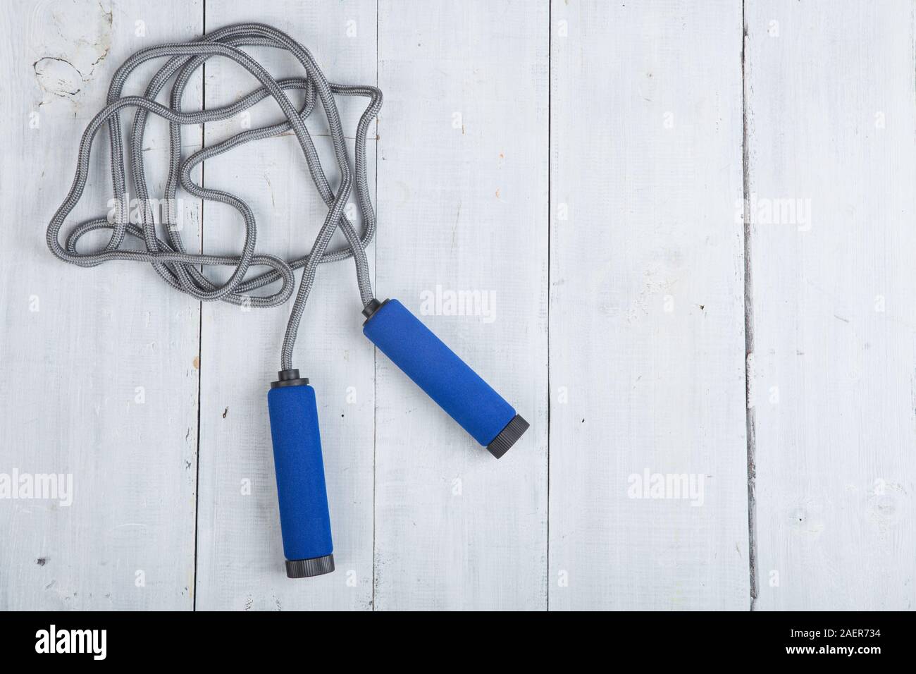 Fitness/sport and healthy lifestyle concept - Jumping/skipping rope with blue handles on white wooden background Stock Photo