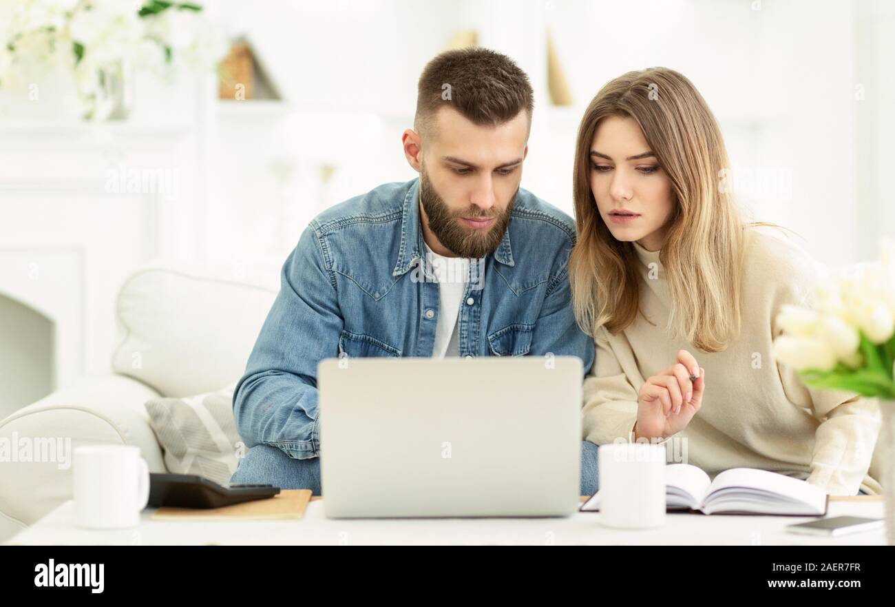 Millennial couple managing expenses with laptop and making notes Stock Photo