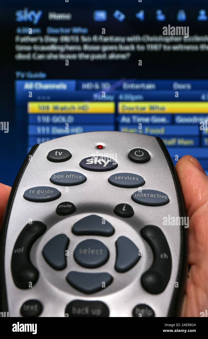 A Man holding a Sky TV remote control, pointing at the TV Stock Photo