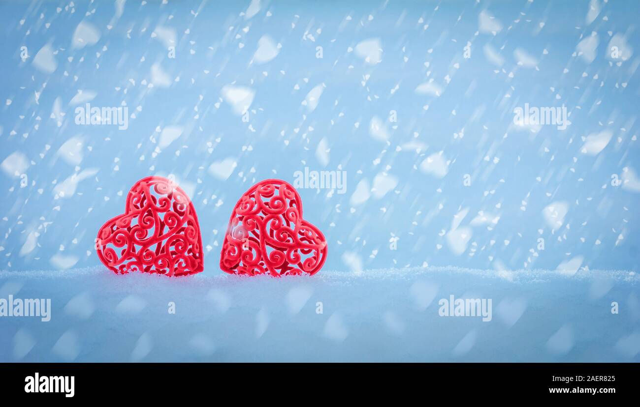 Valentine's Day Valentine card with two red openwork hearts in a snowdrift  on a blue background with falling snowflakes in the shape of hearts with co  Stock Photo - Alamy