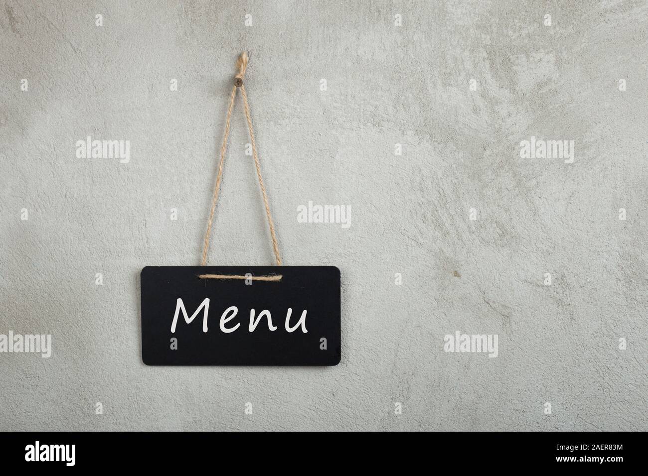 Black notice board, blackboard, chalkboard with text Menu on grey cement wall with copy space Stock Photo