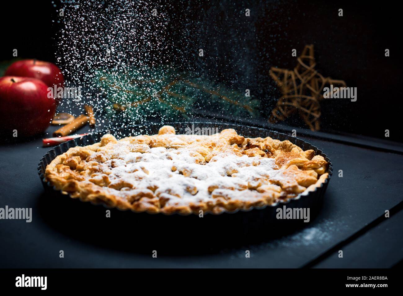 Apple pie sprinkled with sugar on Christmas and winter decorated table Stock Photo