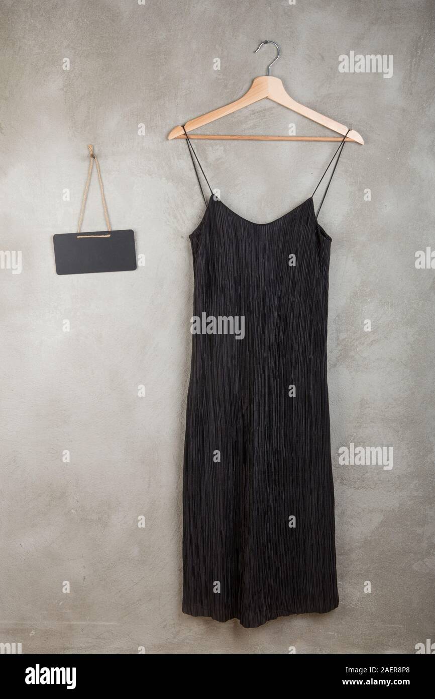 Fashion and shopping concept - blank blackboard and beautiful black dress on a hanger on grey background Stock Photo