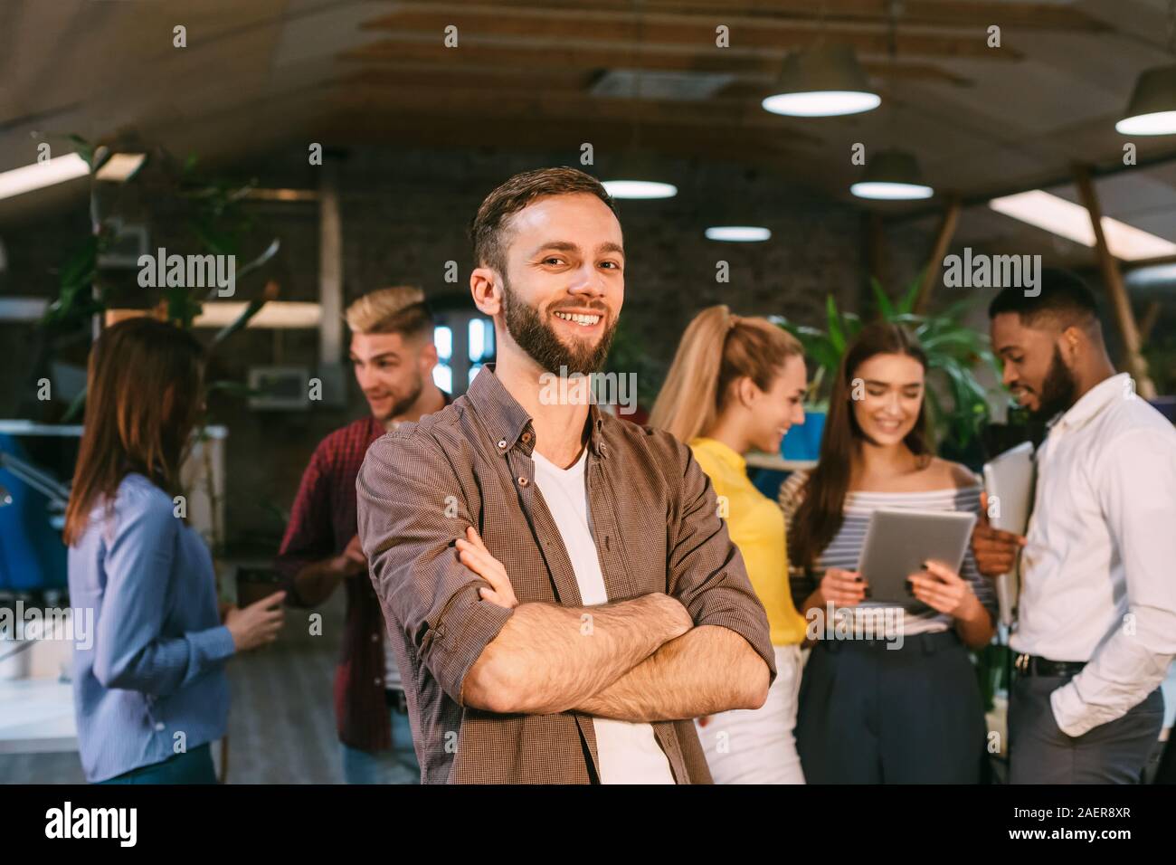 Smm manager smiling to camera, standing in busy creative office Stock
