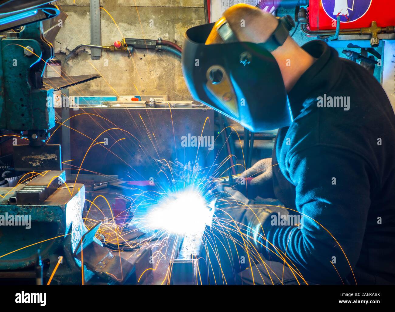 Electric welding process. Worker in welding mask. Yellow sparks fly to the sides. Bright white