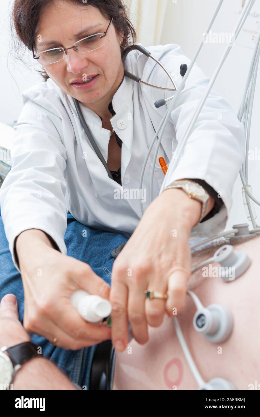 Female cardiologist fitting electrodes  to patients body,Cardiology strees test. Medical examination to measure oxygene quantity used by the patient Stock Photo