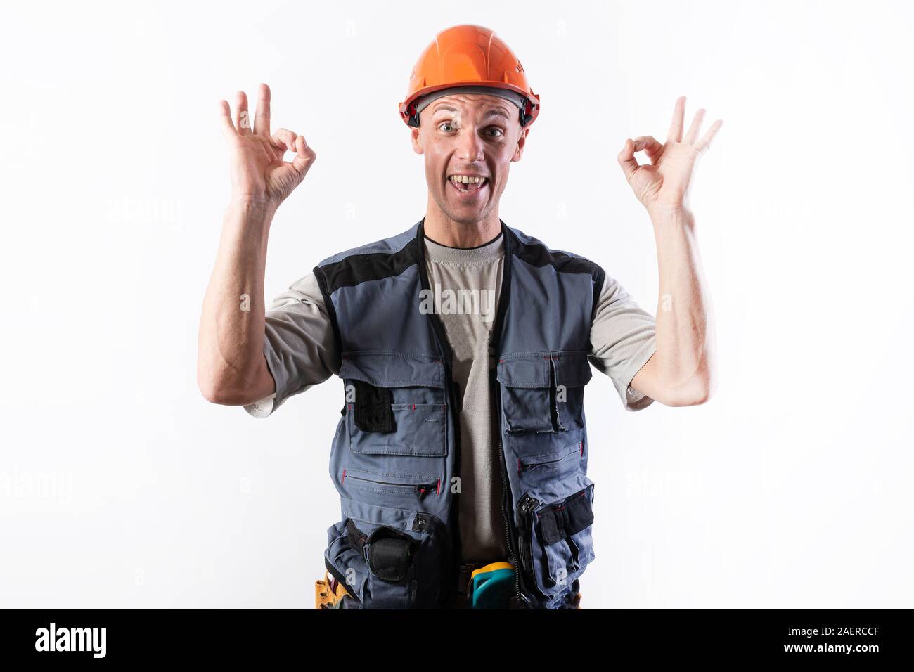 The builder shows the sign okay. In work clothes and a helmet. Stock Photo