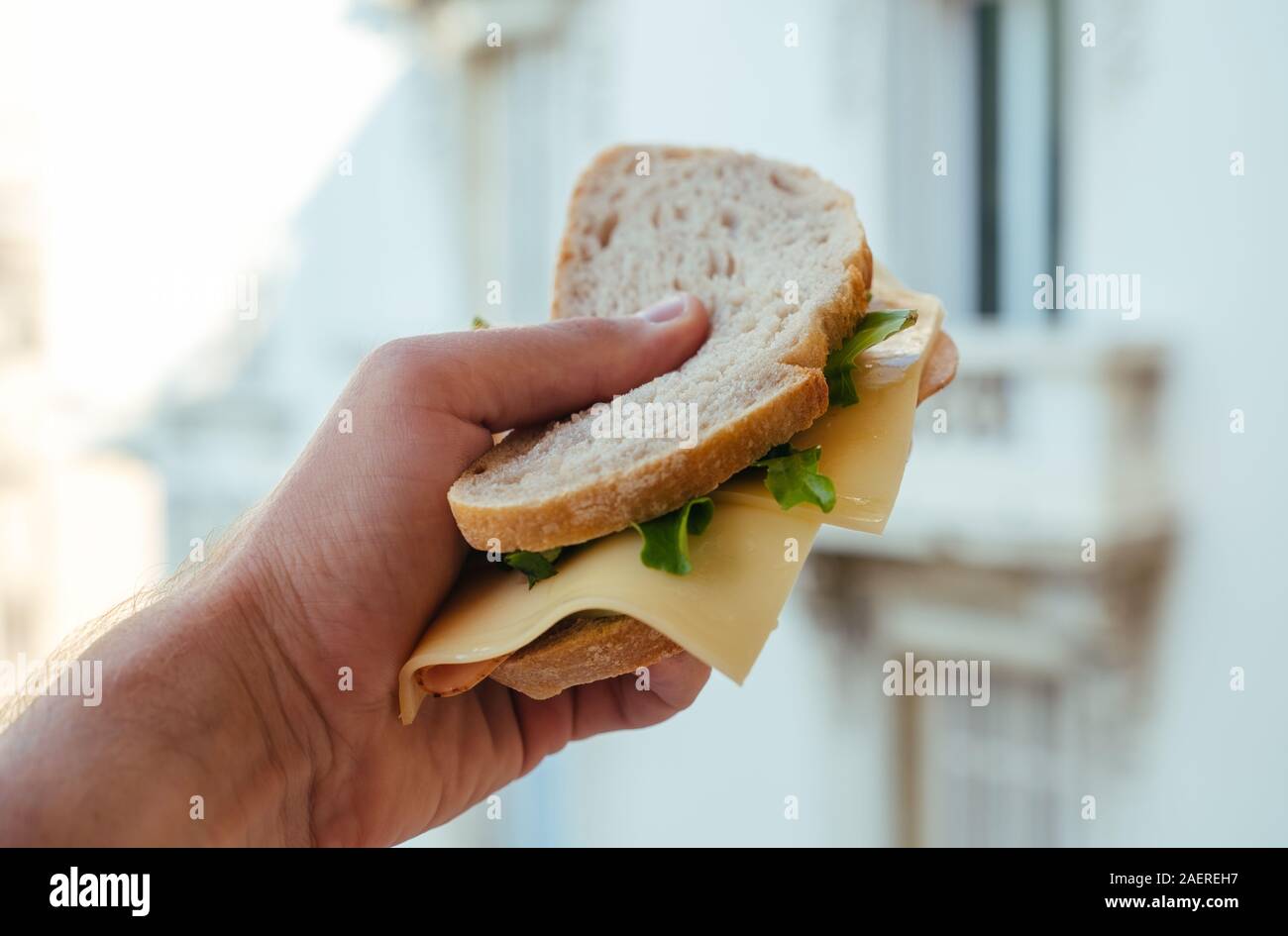 White bread Sandwich with Hum and Salad in man's hand in Monaco Stock Photo