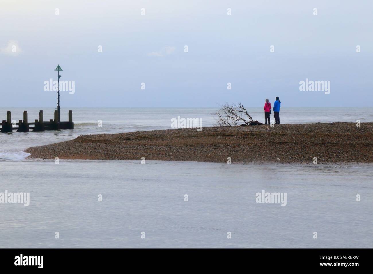 People standing on the pebble beach. Mouth of the river Axe in Devon Stock Photo