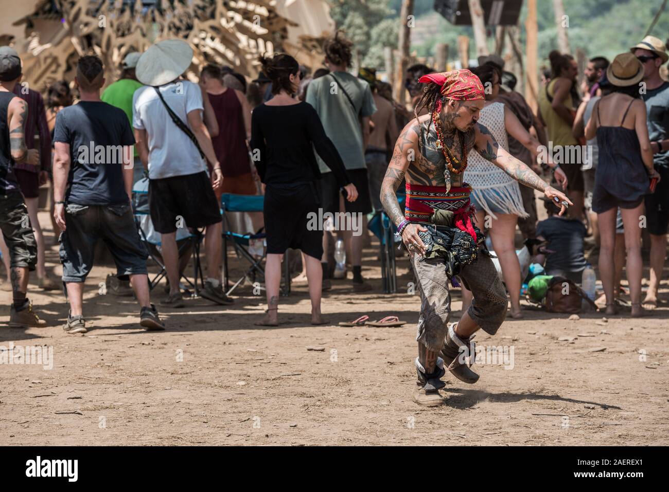 A very tattooed man and pirate scarf dances at the psytrance Lost Theory festival in Riomalo de Abajo Stock Photo