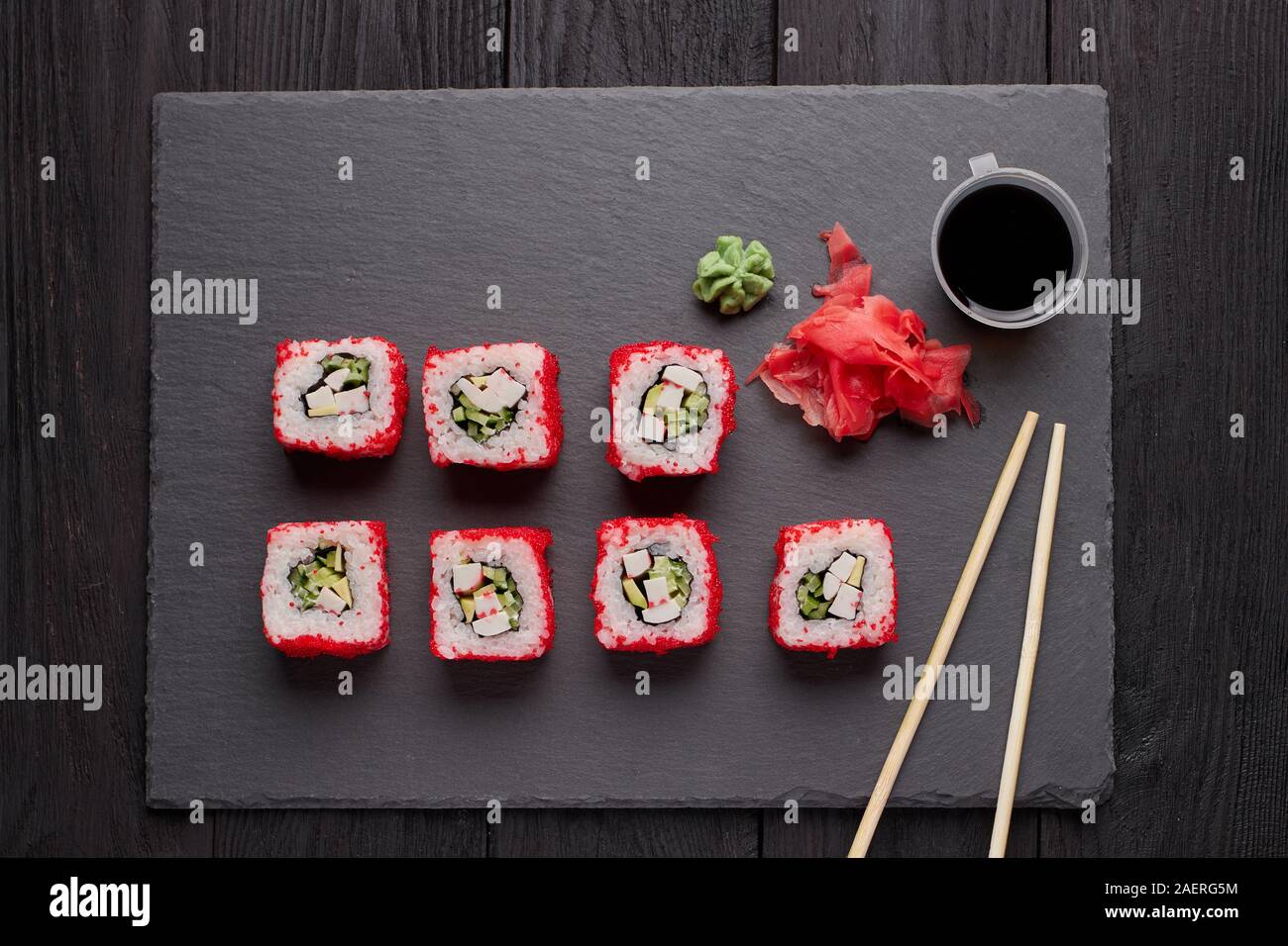 sushi rolls with red chopsticks and sauce on a slate table Stock Photo