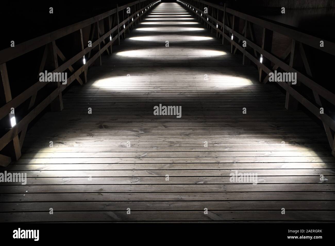 Wooden bridge illuminated by white circular lights at night, perspective Stock Photo