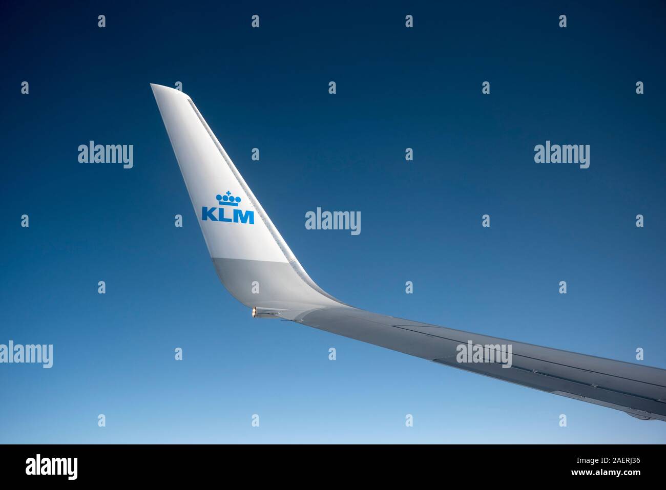 View from a KLM jet showing the wing with the KLM logo against a blue sky . Stock Photo