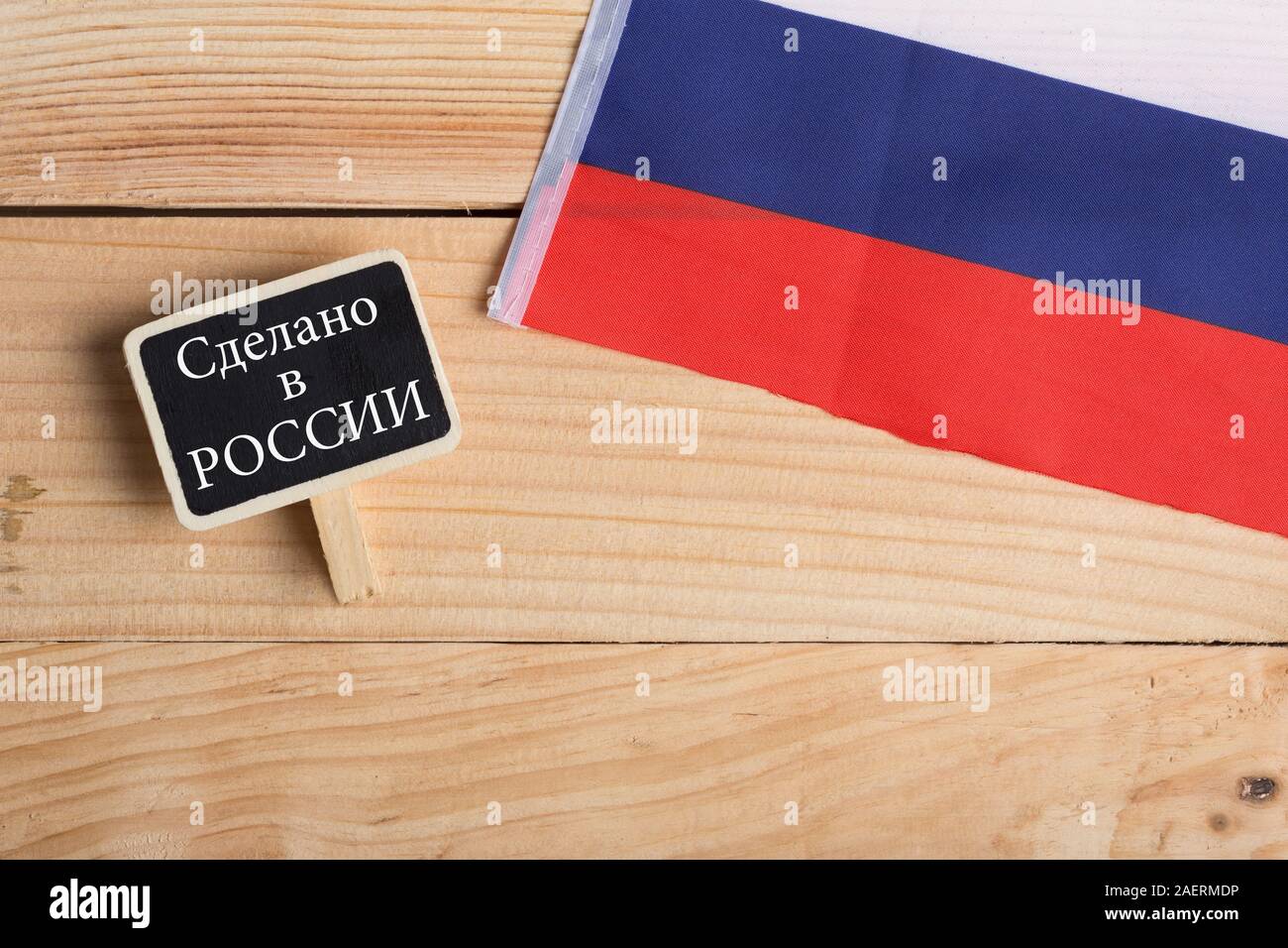 goods and services concept - russian country's flag, blackboard with text in russian language Made in Russia on wooden background Stock Photo
