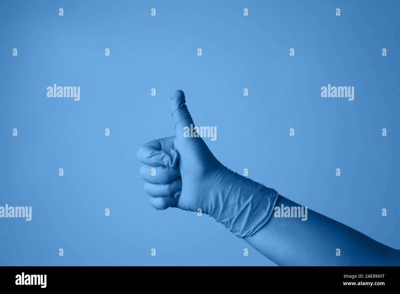 Hand in rubber glove in classic blue. Gesture. Creative composition in minimal style, flat lay. Color trend concept.Horizontal with space for text. Stock Photo