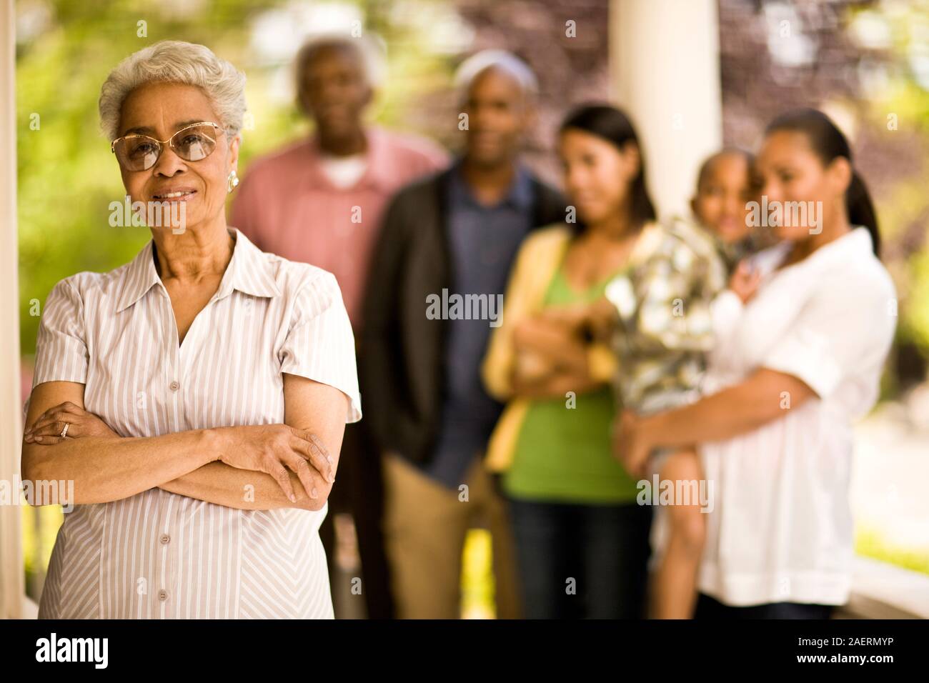 Smiling senior woman poses proudly for a portrait with her family behind her. Stock Photo